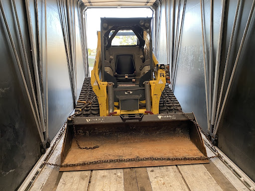 Skid loader loaded in enclosed trailer for transport