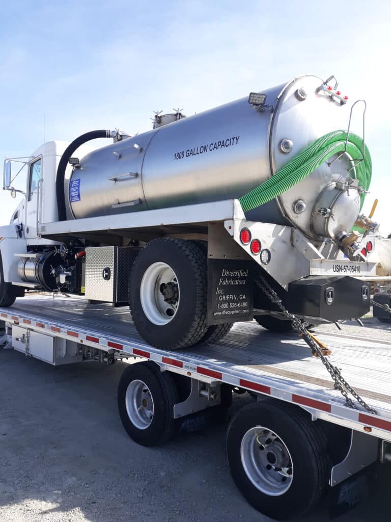 Transporting a vacuum truck on a flatbed trailer.