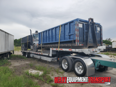 Kenworth Tandem Axle Roll Off Truck With Dumpsters transported on a step deck trailer