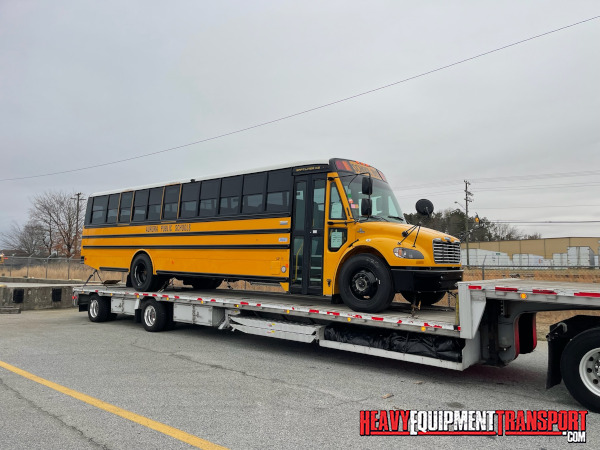 School buses transported on step deck trailer.